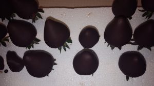 chocolate dipped strawberries on toothpicks stuck in a foam sheet