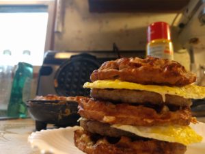 chaffle sandwich on a plate sitting in front of a waffle maker